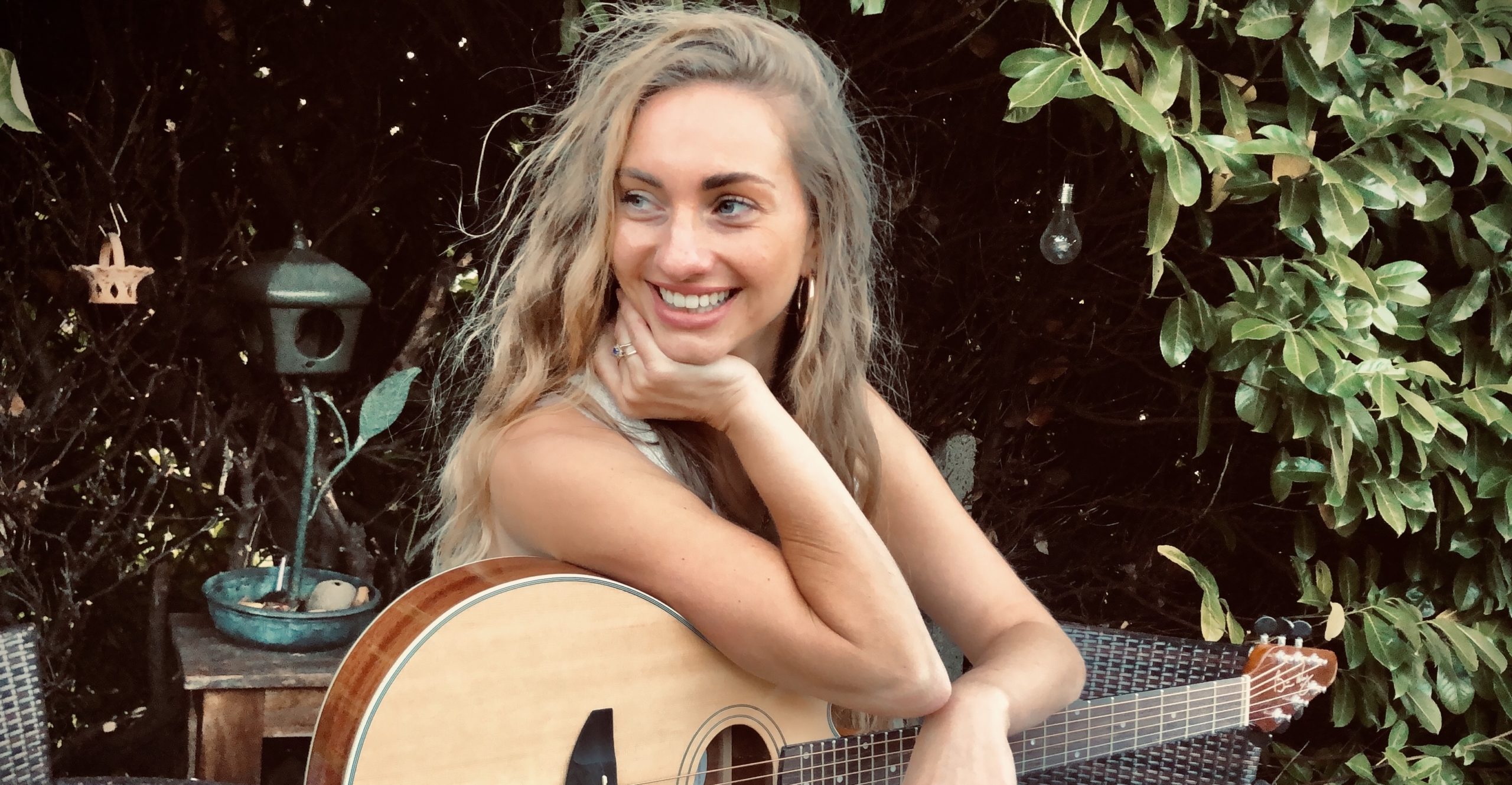 Talia sits with her guitar